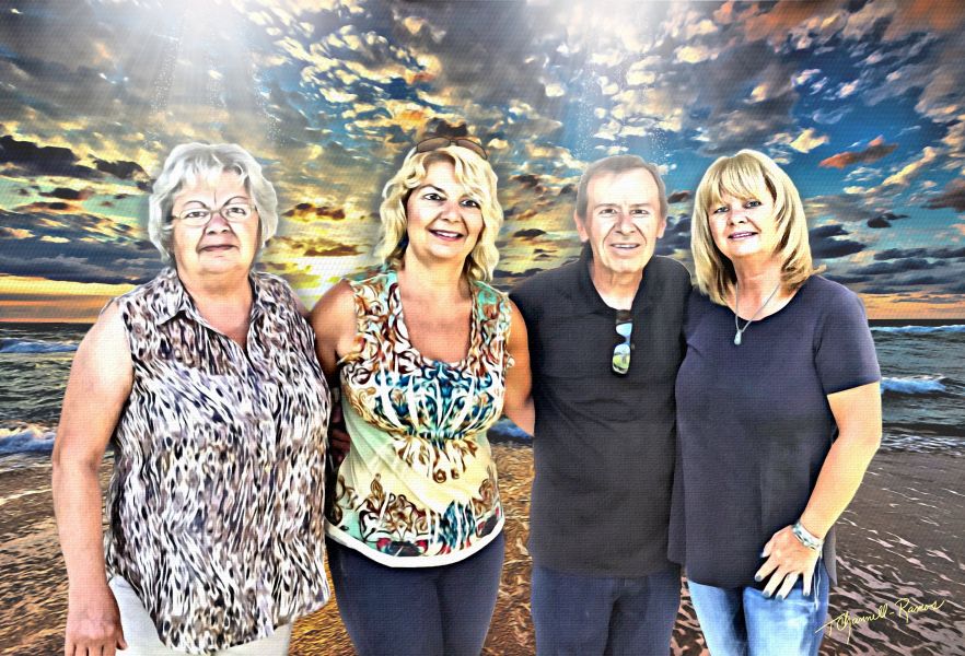 Four people standing together on a beach with a colorful sky background